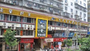 A multi-story building with various shops on the ground floor, including a visible store with a prominent sign. - Jiu Tian Fashion Hotel (Fuzhou)