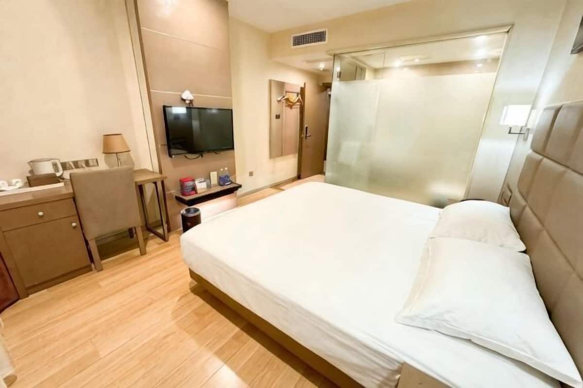 Ein Hotelzimmer mit Bett, Schreibtisch, Fernseher und Badezimmer.