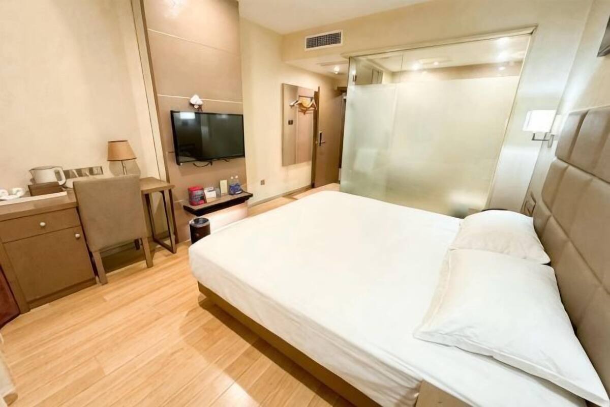 Una habitación de hotel con cama, escritorio, televisor y baño.