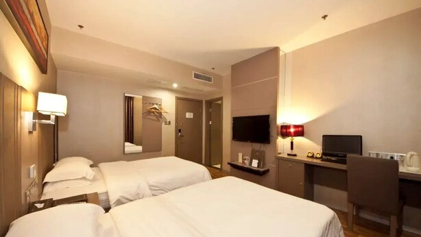 A hotel room with two beds, a desk with a computer, a TV, and a lamp. - Jiu Tian Fashion Hotel (Fuzhou)