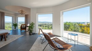 A spacious room with a large balcony, a dining area, and a seating area with a view of the countryside. - Exclusive villa with padel court [03] (Lagos)