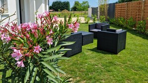 A patio area with outdoor furniture, a white building, and a wooden fence.