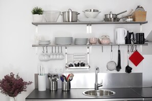 A kitchen with stainless steel appliances, white cabinets, and various kitchen utensils and cookware.