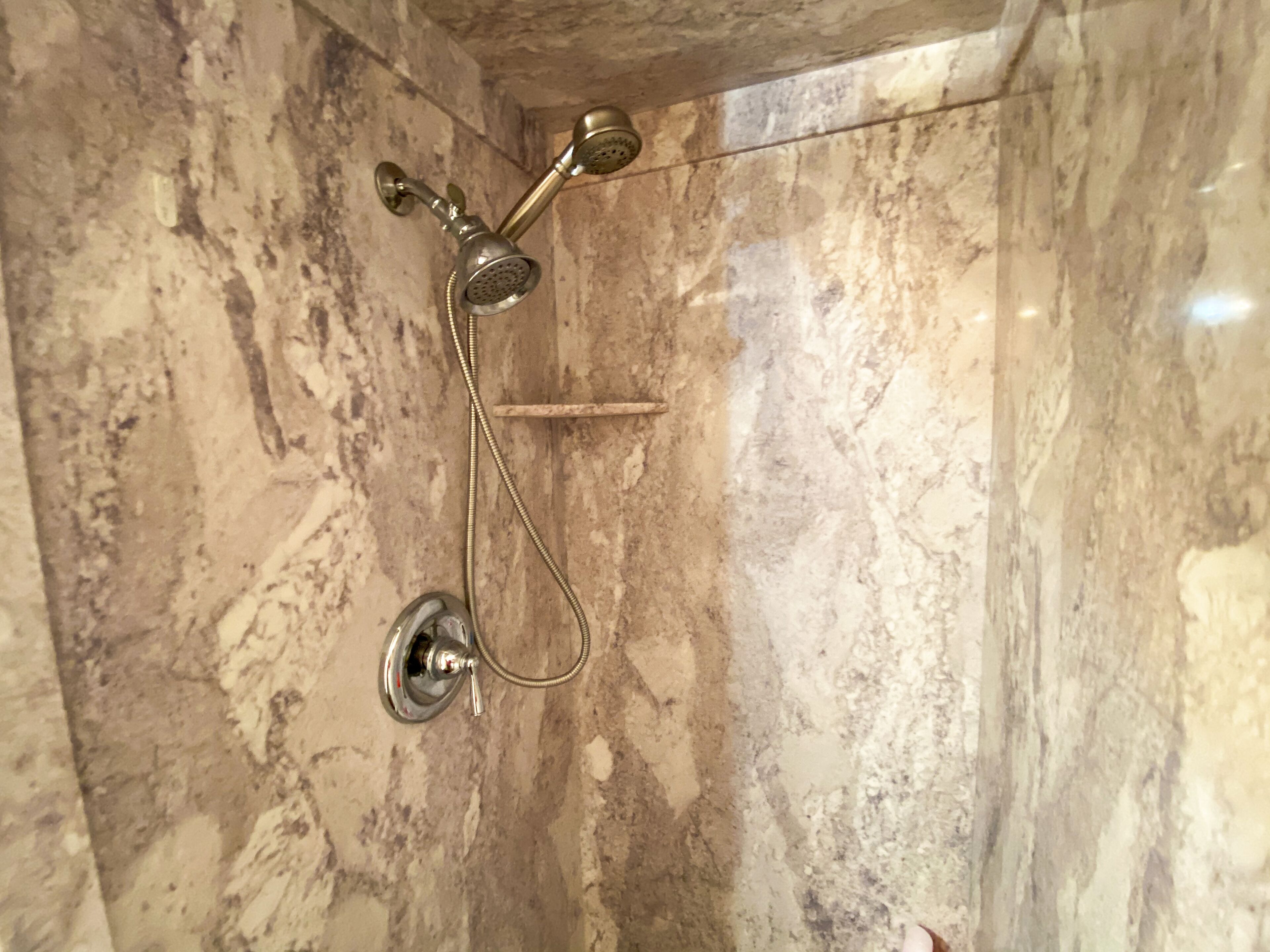 Une douche équipée d’un pommeau de douche à main et d’un robinet mural.
