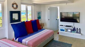 Una camera da letto con un letto, una televisione e vista sul mare.