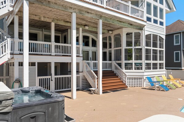 A two-story house with a covered porch, a hot tub, and outdoor seating. - 7th Heaven: Private Pool, Spa, Game Room (Corolla)