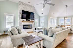 Relax in this spacious living room with a high ceiling, flat-screen TV, and comfortable sectional sofa.
