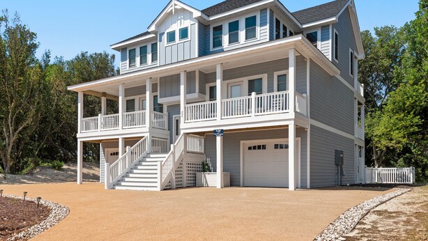 Une maison à deux étages avec un porche à l’avant, un garage et un escalier menant à l’étage supérieur.