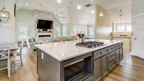 Une cuisine spacieuse dotée d’un grand îlot central, d’appareils électroménagers modernes et de luminaires suspendus.