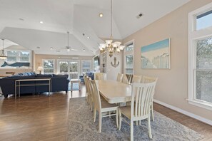 A spacious living room with a large dining table, a sofa, and a chandelier.
