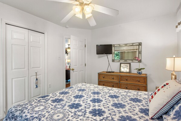 A bedroom with a bed, dresser, TV, and ceiling fan. - Endless Sunsets in Corolla Light: Pool, Spa, Club Amenities & Golf Discounts! (Corolla)