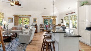 A spacious living room with a large sofa, a coffee table, and a dining area with a kitchen island. - Endless Sunsets in Corolla Light: Pool, Spa, Club Amenities & Golf Discounts! (Corolla)