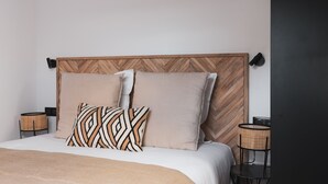 A bed with a wooden headboard, two pillows, a blanket, and two side tables with lamps. - Appartements Crébillon - Maisons du Monde Hôtel & Suites (Nantes)