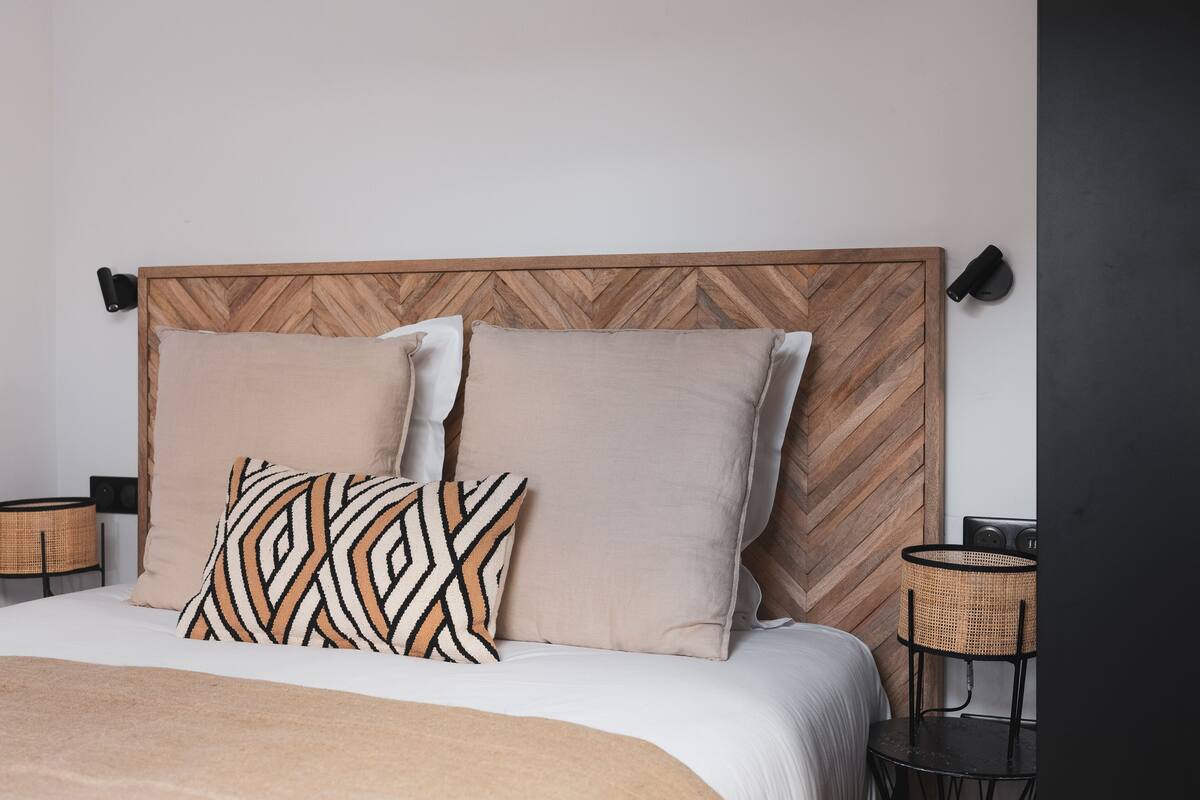 A bed with a wooden headboard, two pillows, a blanket, and two side tables with lamps.