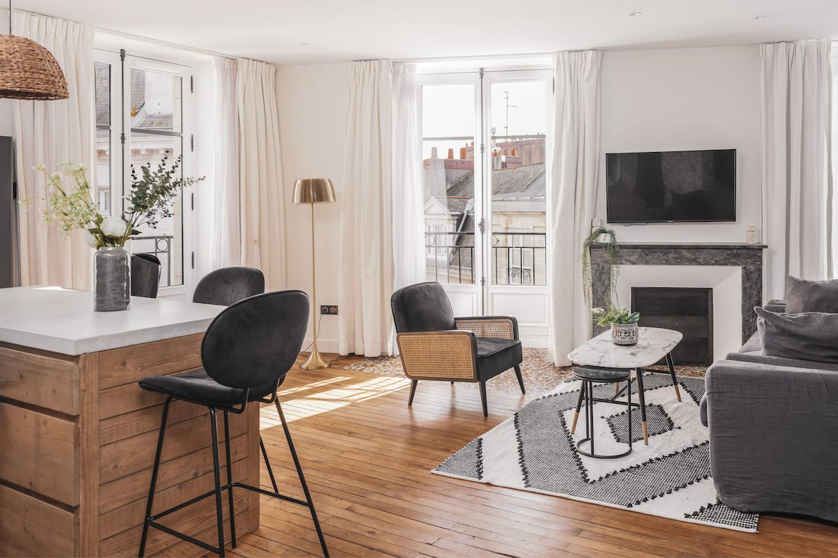 A modern living room with a fireplace, a television, and a dining area with bar stools.