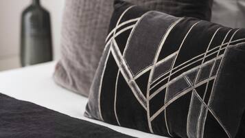 Una cama con un cojín estampado en blanco y negro y un cojín gris con textura.