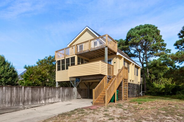Une maison en bois à deux étages, dotée d’un balcon et d’un escalier menant à l’étage supérieur.