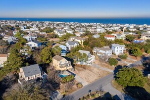 Vue aérienne d’un quartier résidentiel avec des maisons, une plage et une jetée au loin.