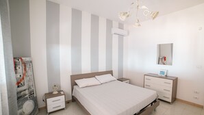 A bedroom with a large bed, a nightstand, a dresser, a mirror, and a chandelier.