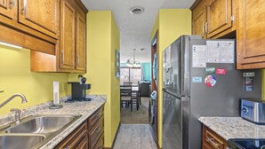 A kitchen with wooden cabinets, a stainless steel refrigerator, and a granite countertop.