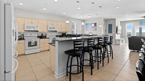 A modern kitchen with a central island, bar stools, and built-in appliances.