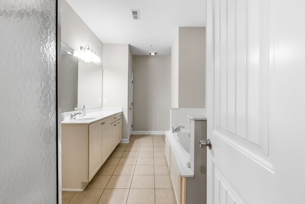 Un baño moderno con un espejo grande, un lavamanos y una bañera.