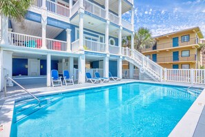 A pool area with a clear blue pool, white railings, and blue lounge chairs.