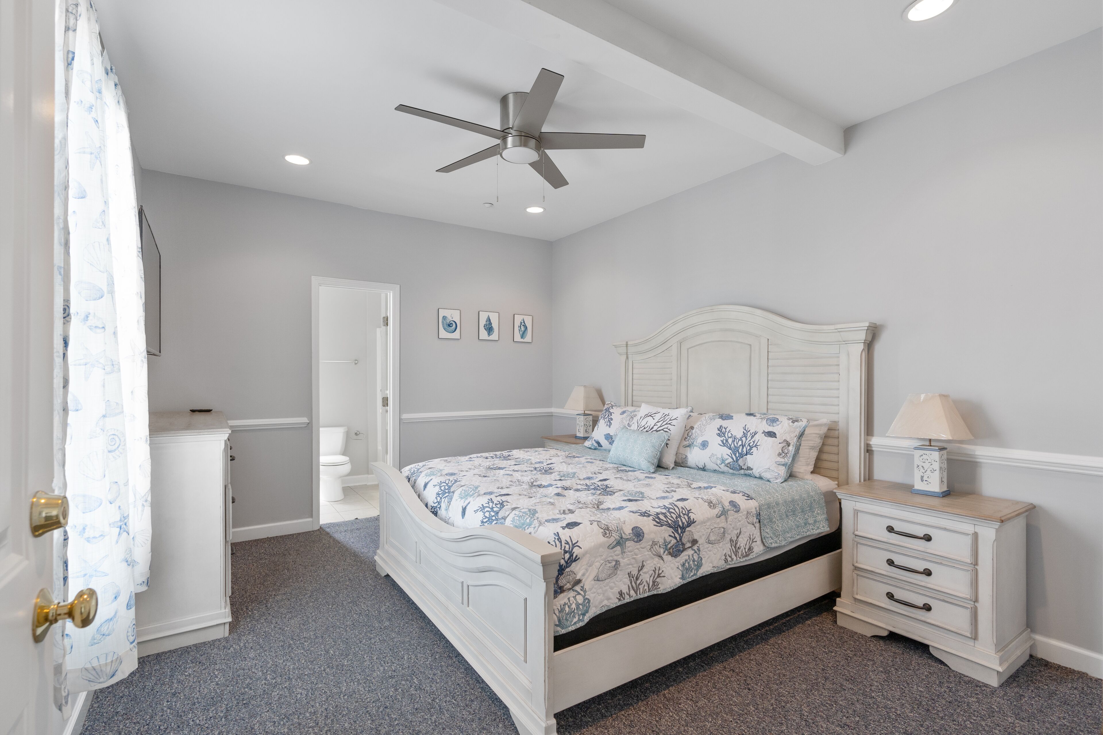 Une chambre à coucher avec un lit, une table de chevet, un ventilateur de plafond et une porte.