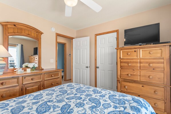 A bedroom with a bed, dresser, television, and a door.