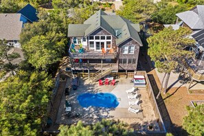 A two-story house with a large deck, a swimming pool, and a fenced backyard. - Take It E-Sea: Private Pool, Hot Tub, Rec Room (Nags Head)