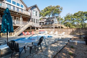 A backyard with a swimming pool, lounge chairs, and a wooden deck.
