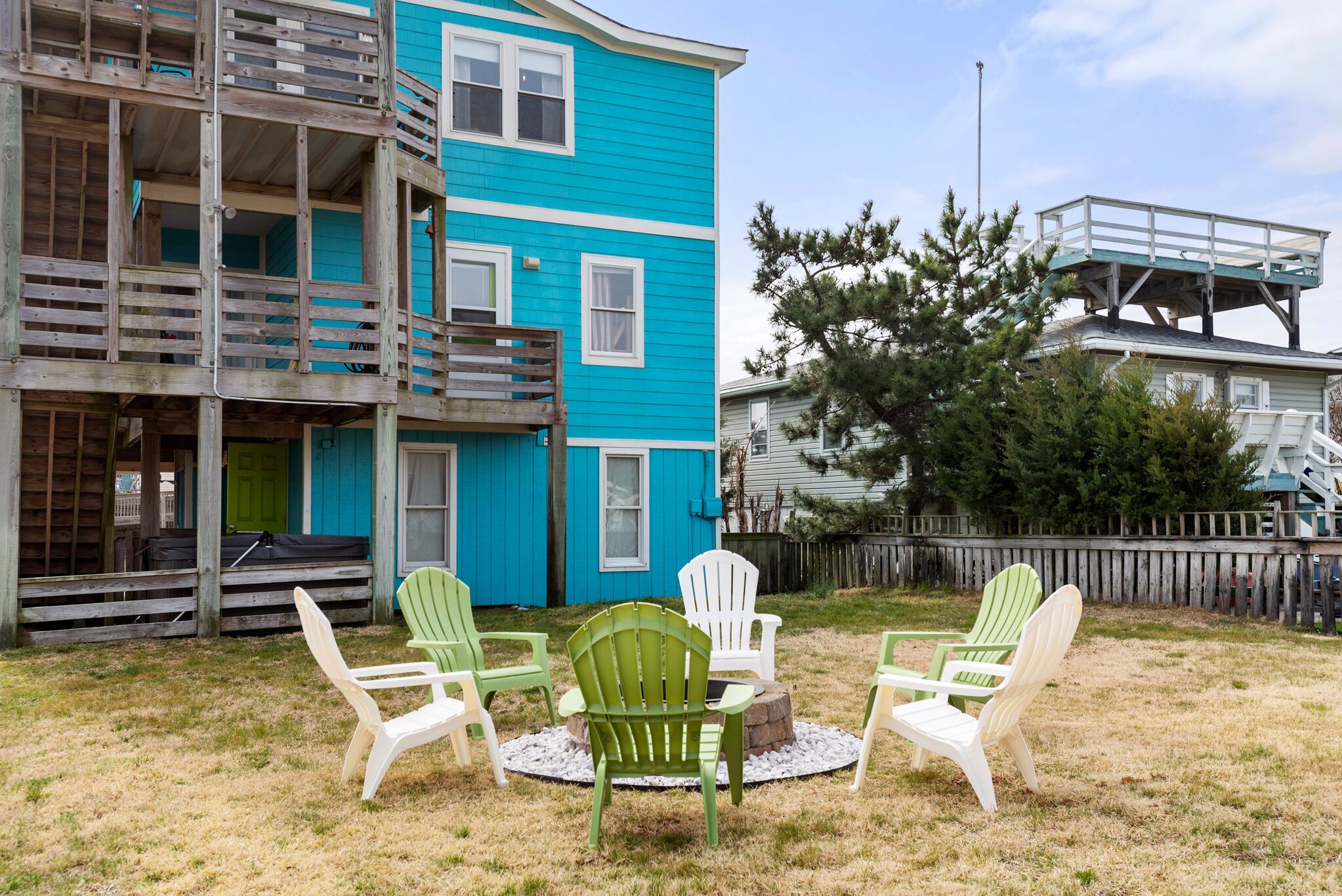 A two-story blue house with a wooden deck and a raised platform.