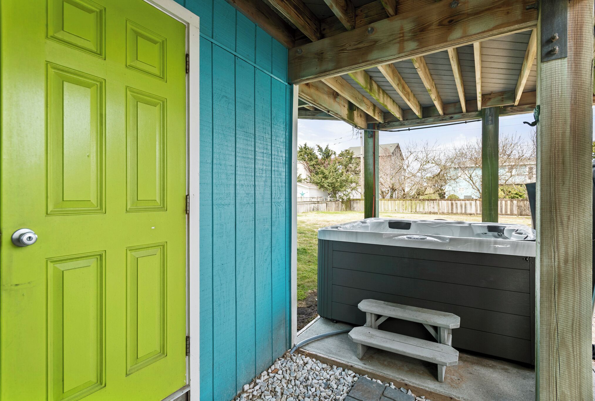 A covered outdoor area with a hot tub and a wooden deck.