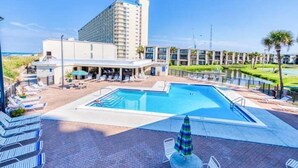 Un hotel con piscina, sillones de descanso y vista al océano.