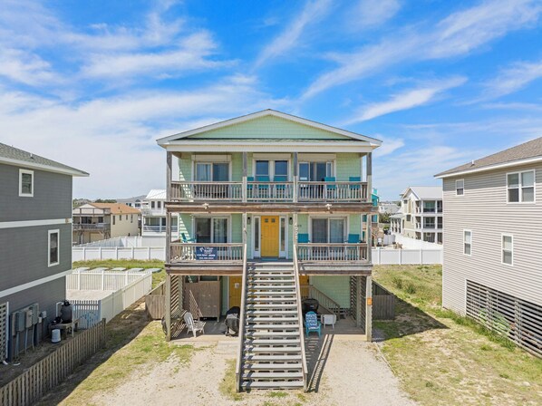 A two-story building with a balcony on the second floor, a front door, and a staircase leading to the entrance. - Surf's Up: Semi-Oceanfront, Hot Tub, Awesome Views (Kitty Hawk)