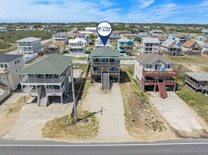 A coastal residential area with multiple two-story houses, some with balconies, and a prominent blue house with a green roof.