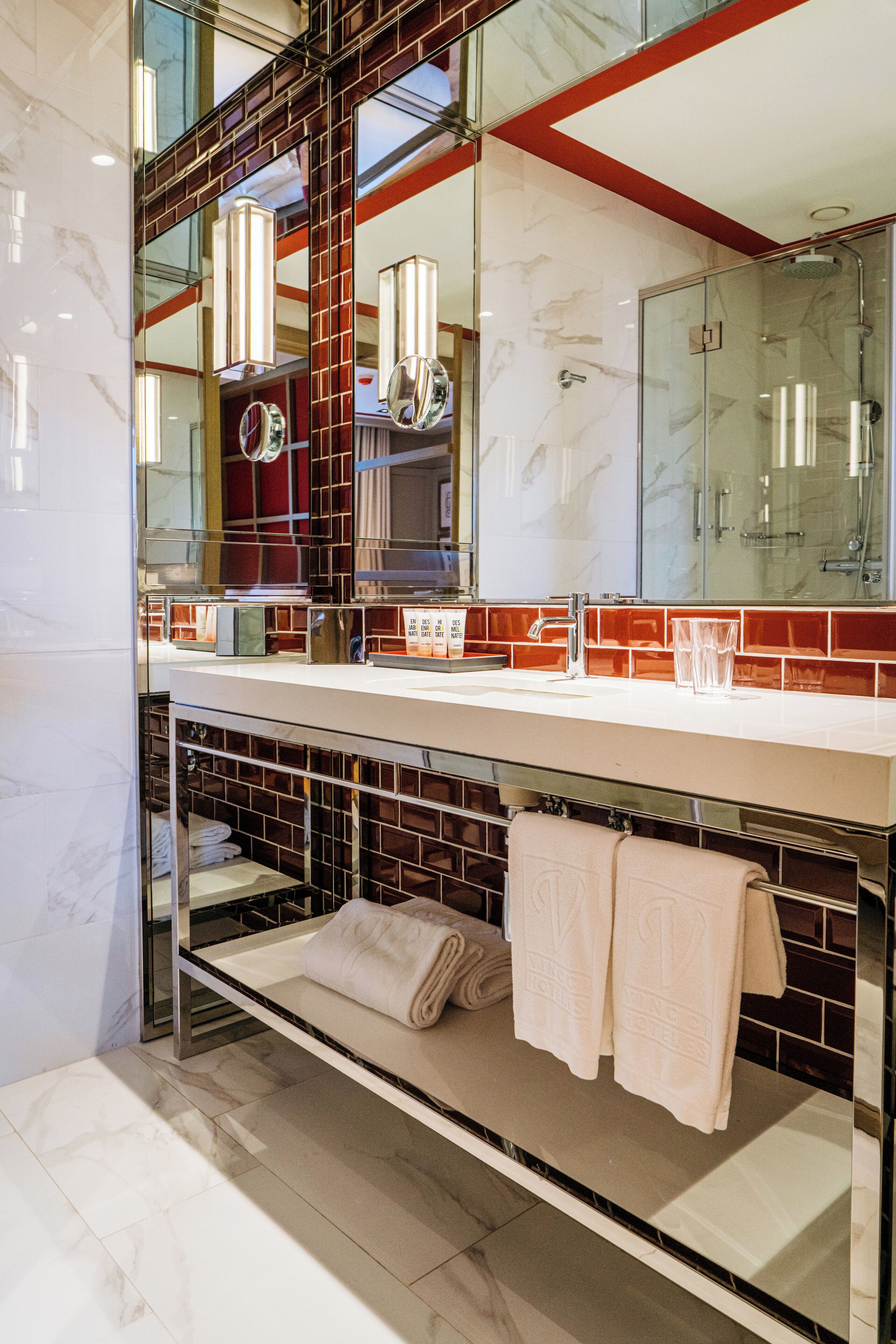 A modern bathroom with a large mirror, a glass shower enclosure, and a towel rack.