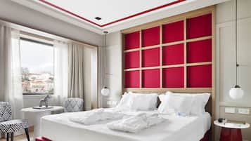 Ein modernes Hotelzimmer mit einem großen Bett, Blick auf die Stadt, einem kleinen runden Tisch und einem Stuhl.