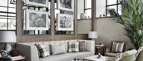 A modern living room with a sofa, armchairs, a coffee table, and a large window.