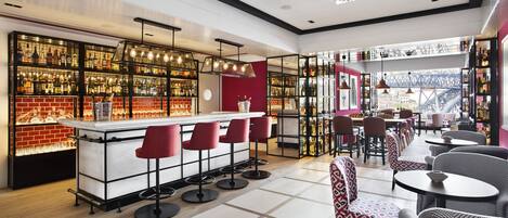 A modern bar area with a brick wall, multiple shelves of bottles, and red bar stools.