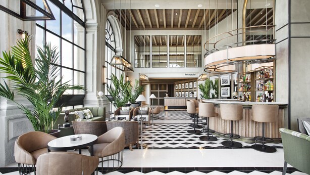 A spacious lobby with a checkered floor, a reception desk, seating area, and a bar with a curved counter. - Hotel Vincci Ponte de Ferro (Vila Nova de Gaia)