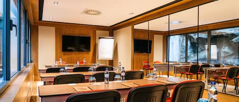 A conference room with long tables, chairs, water bottles, and a whiteboard.