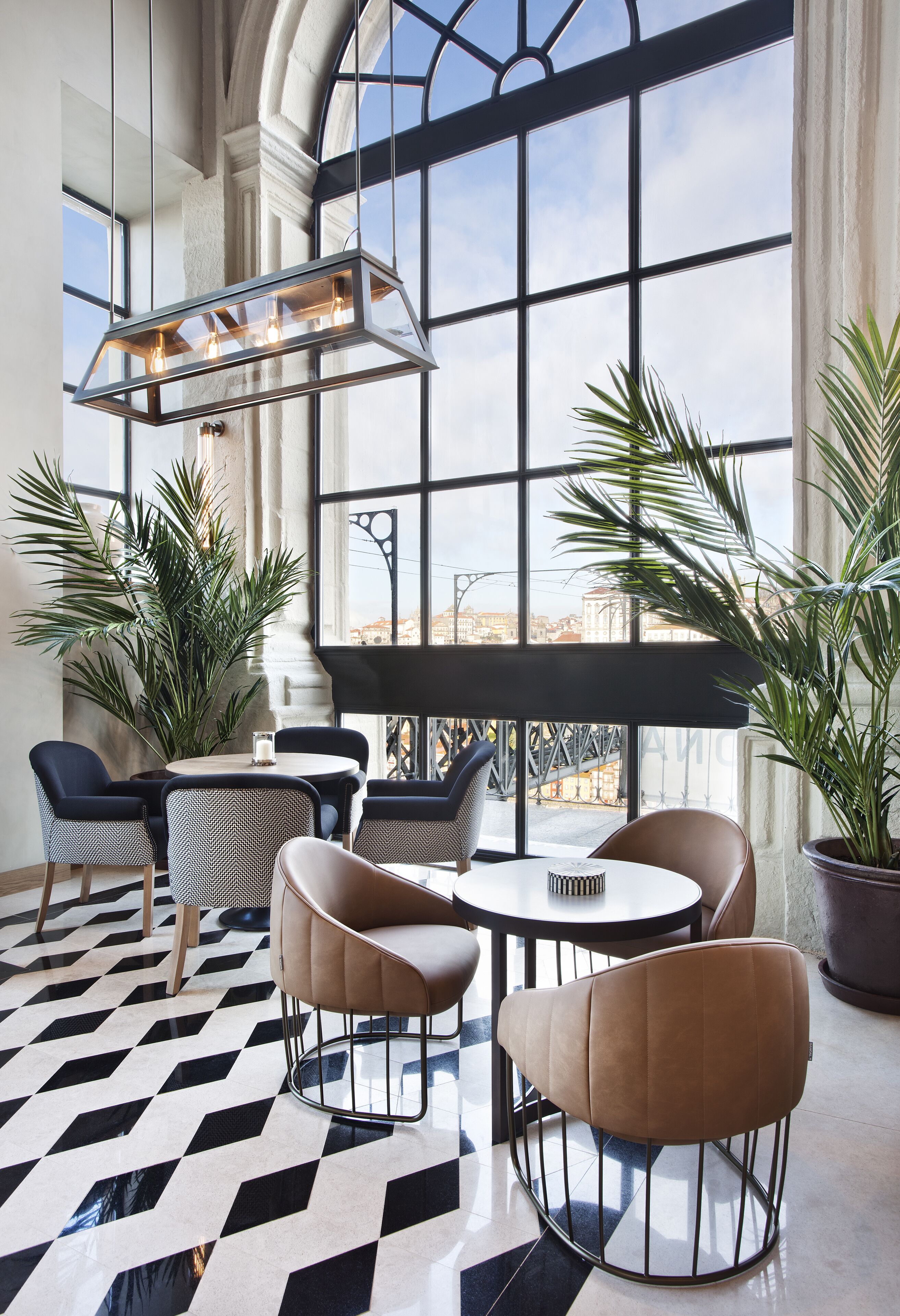 Un salón moderno con un ventanal grande, piso con patrón geométrico y mobiliario contemporáneo.