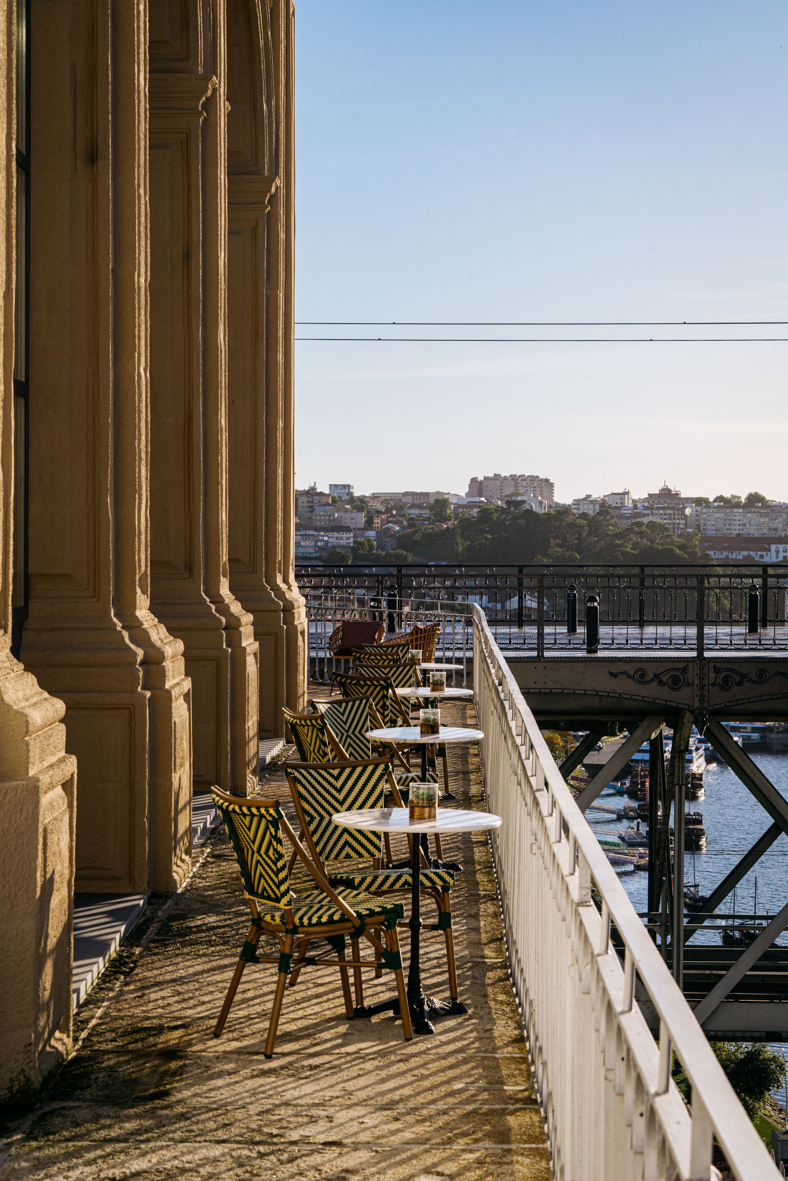 A terrace with outdoor seating, overlooking a river and cityscape.