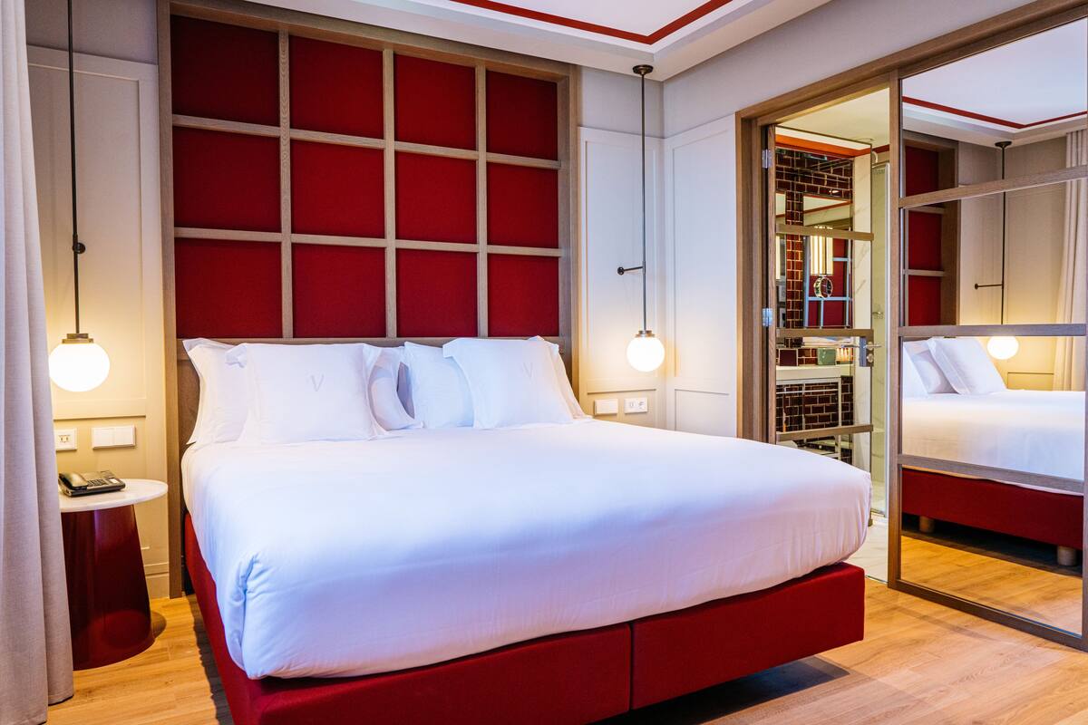 Een moderne hotelkamer met een groot bed, een rood hoofdeinde en een inloopkast.