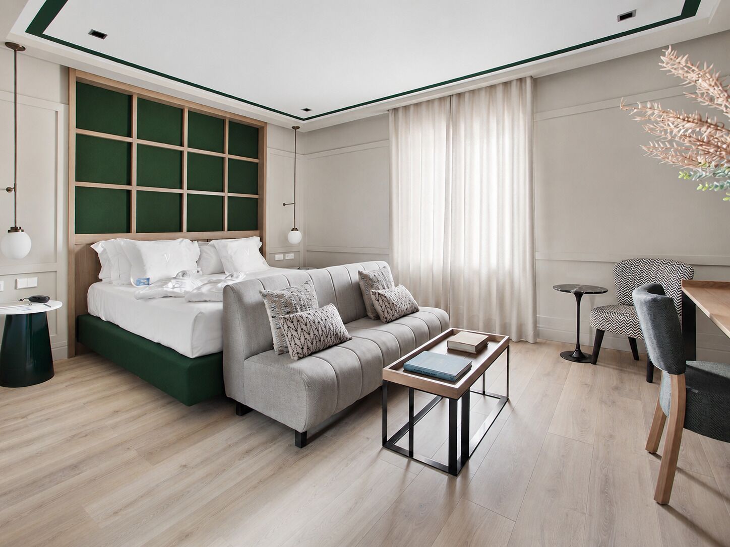 Quarto de hotel moderno com cama, sofá, mesa de centro e escrivaninha com cadeira.