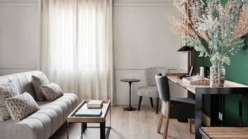 A modern living room with a sofa, coffee table, and a dining area with chairs and a table.