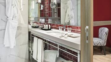 Une salle de bain moderne avec un grand miroir, un meuble-lavabo doté d’un porte-serviettes et une chaise.