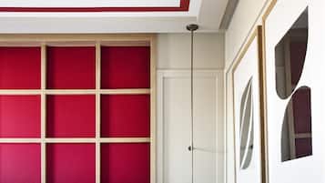 A hotel room with a bed, a bedside table, a wall-mounted light, and a door.