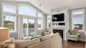 Un salón amplio con televisor grande, asientos cómodos y chimenea.